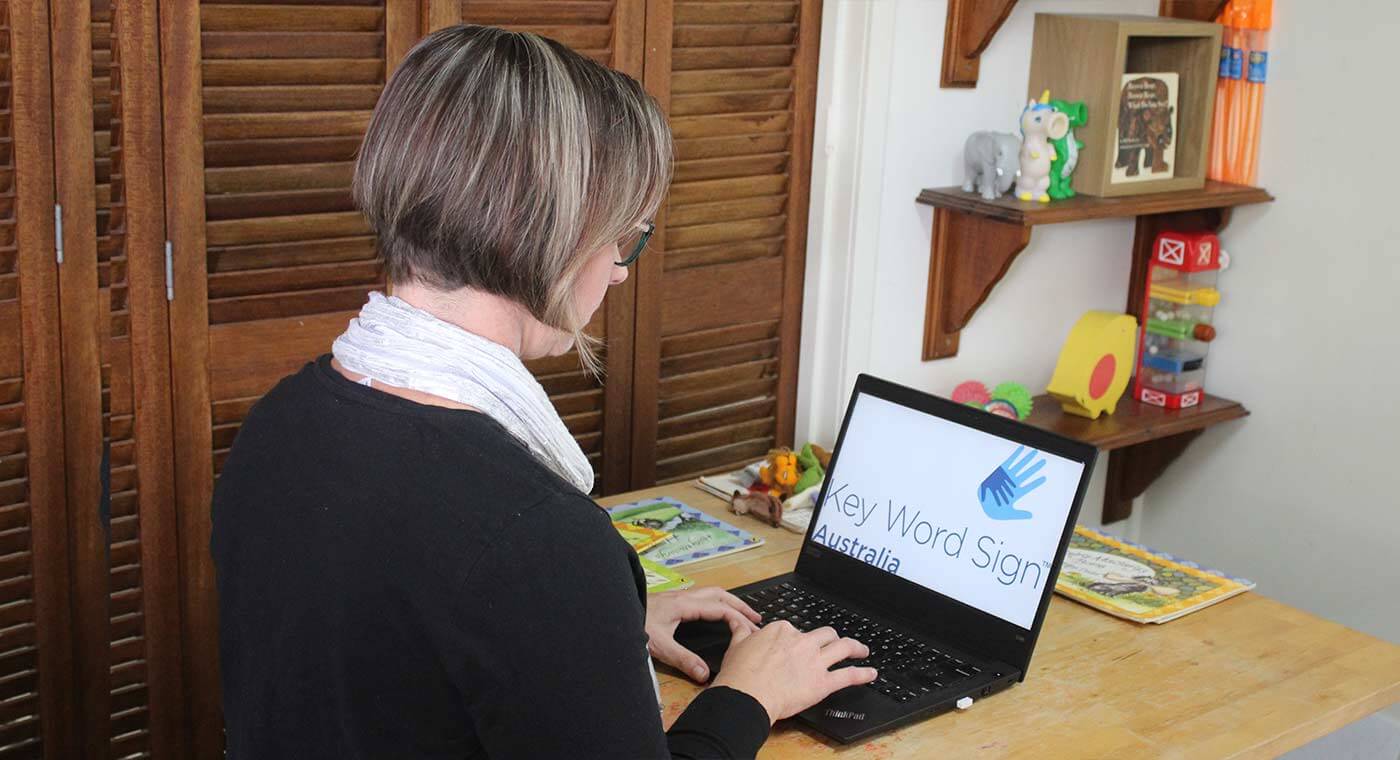 Lauren Scott, online speech therapist, sitting a desk with laptop.